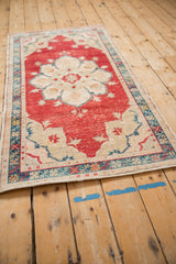 Angled view of a distressed Turkish Oushak's corner showing the low-pile texture and spandrel detail.