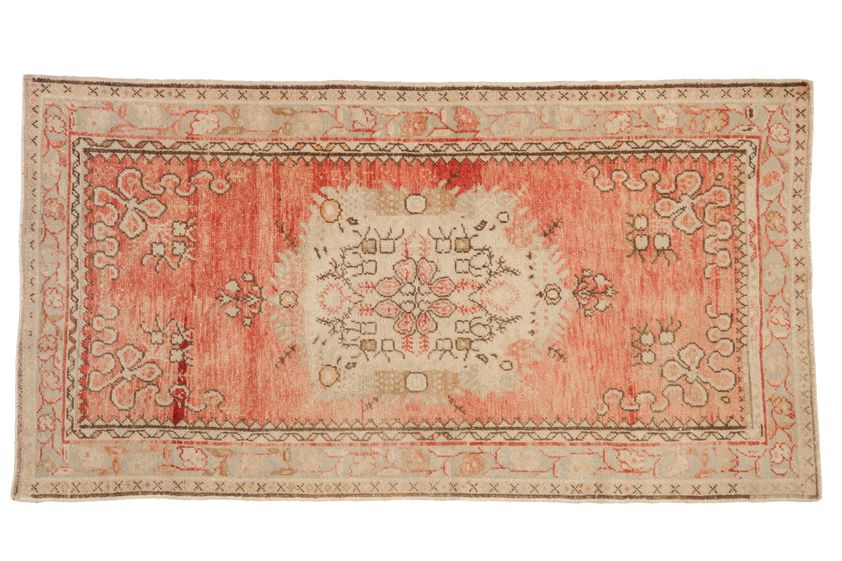 Vintage distressed Oushak rug with a floral medallion on an abrashed field of dusty rose, blush, and ivory.