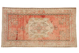 Vintage distressed Oushak rug with a floral medallion on an abrashed field of dusty rose, blush, and ivory.