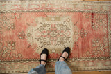 A view of the time-softened texture of a vintage Oushak rug shown underfoot for scale.