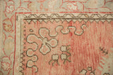 Evenly worn corner of a vintage Oushak rug, showing cloud band and floral motifs in dusty rose.