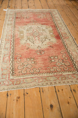 Angled perspective of a vintage Oushak rug showing the abrashed dusty rose field and central medallion.
