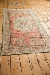 Angled perspective of a vintage Oushak rug showing its abrashed dusty rose and ivory design.