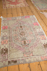 Angled view of a decorative distressed Oushak rug with faded silver, aubergine, and pink tones.