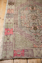 Textural wear on the corner of a distressed Oushak rug with soft aubergine and bubblegum pink accents.