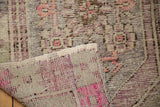 Corner of a distressed Oushak rug showing its worn pile and colorful hand-knotted reverse.