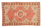 Distressed Oushak rug with a geometric medallion in faded raspberry, saffron yellow, and platinum tones.