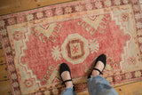 Faded raspberry red and worn texture of a distressed Oushak rug shown to scale.