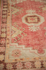 A distressed Oushak rug's low pile, showing faded floral borders and geometric patterns.