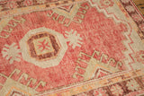 Close-up of the distressed Oushak rug's pile, showing mostly even wear to the raspberry red knot heads.