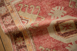 Softly folded vintage Oushak rug showing its low pile texture in faded raspberry and platinum.