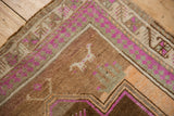 Distressed Kars rug corner: worn pile, pale magenta, chocolate brown, animal motif, pawn border.