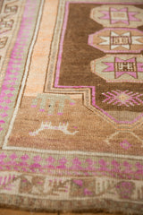 Distressed Kars rug detail: brown field with geometric motifs, magenta, and tangerine borders.
