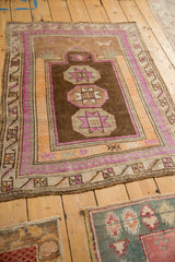 Distressed vintage Kars rug corner with geometric pawn border and faded magenta, tangerine tones.