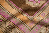 Distressed Kars rug corner shows geometric pawn pattern, faded pile in brown, magenta, orange.