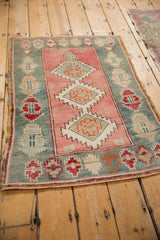 A distressed vintage Oushak rug from an angle, showing its decorative geometric design and faded colors.