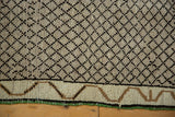 Distressed Kars rug's charcoal lattice, ivory ground, decorative border, and green selvage.