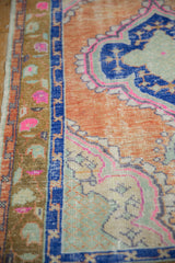 Vintage distressed Oushak rug detail: cantaloupe field, sapphire blue border, and worn trellis motif.