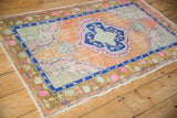 Corner view of distressed Oushak rug with time-softened cantaloupe field, cobalt blue, and bronze borders.