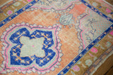Distressed cantaloupe field with sapphire blue scalloped motif and magenta details on vintage Oushak rug.