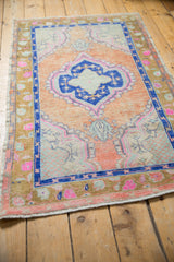 Distressed Oushak rug border showing dusty gold, magenta motifs, cobalt blue, and worn pile.