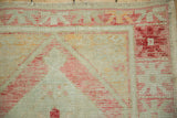 Detail of the worn, hand-knotted pile on a vintage Oushak corner with ruby and tangerine tones.