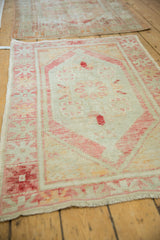 A distressed vintage Oushak rug with decorative wear, shown at an angle on a wood floor.