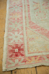 Intact side cord selvage on a vintage Oushak rug with worn, low pile and ruby motifs.