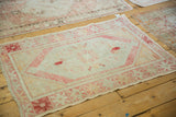 Distressed vintage Oushak rug in a ruby and silver palette, viewed with other vintage textiles.