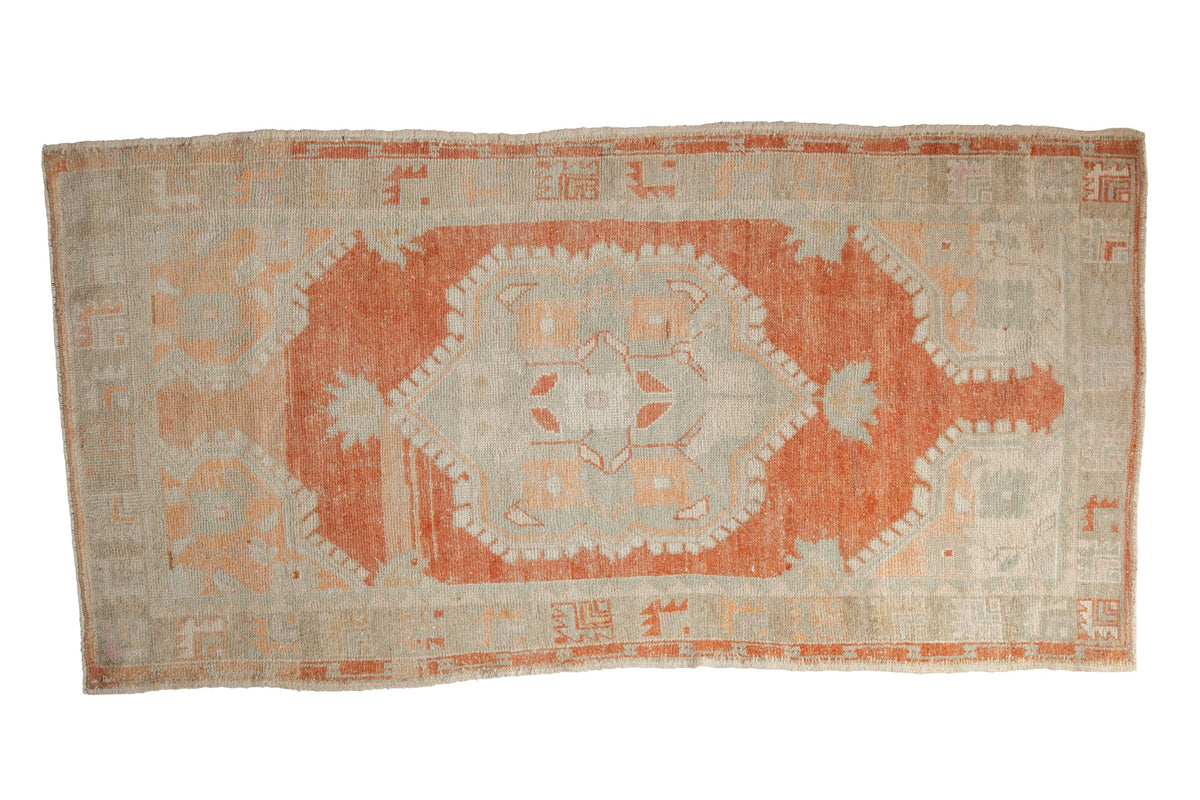 Distressed Oushak runner featuring an oversized floral medallion in rust, seafoam green, and ivory.