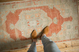 Distressed vintage Oushak runner featuring an abrashed terra cotta field with pale green geometric blossoms.