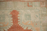Distressed vintage Oushak runner pile with rust, pale green, and ivory geometric motifs.