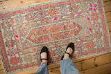 Distressed Oushak rug section, showing magenta, aubergine, green motifs, with areas of wear.