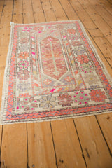 Distressed Oushak runner displaying floral border, pinwheel spandrel, and magenta accents.