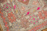 Vintage distressed Oushak runner's main border with floral top views, magenta pinwheel motifs, and wear.