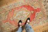 A vintage distressed Oushak runner's faded medallion in blush, brick red, and soft seafoam green.
