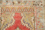 Distressed Oushak rug corner showing spandrels in seafoam green, pale brick red, and tangerine orange.