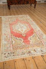 Angled view of a vintage Oushak runner's distressed, low-pile texture and blush medallion.