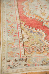 Low-pile texture on the seafoam green border and red field of a vintage distressed Oushak rug.