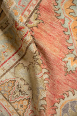 Folded vintage Oushak runner showing its abrashed dusty blush field and textured low pile.