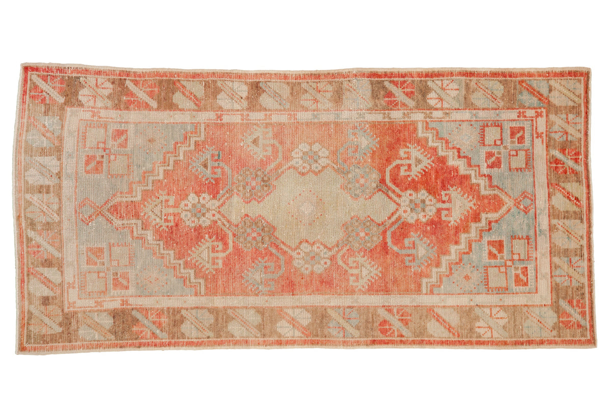 Vintage distressed Oushak runner with a faded geometric medallion in pale watermelon and powder blue.