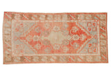 Vintage distressed Oushak runner with a faded geometric medallion in pale watermelon and powder blue.