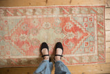 A person's view showing the scale and time-softened pile of a distressed Oushak runner.