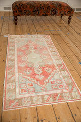 Distressed Oushak runner viewed from an angle, highlighting its soft pale watermelon and blue hues.