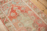 Low pile texture of a distressed Oushak rug with faded strawberry and powder blue geometric blossoms.