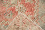 A distressed Turkish Oushak rug's corner folded to reveal the hand-knotted pile and woven foundation.