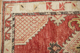 Lattice design corner spandrel and serpent motif border of a distressed Turkish Oushak rug.
