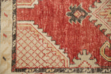 Corner detail of a distressed Oushak runner showing the red lattice spandrel and worn texture.