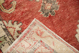 Folded corner revealing the hand-knotted back and distressed cherry red pile of a vintage Oushak rug.