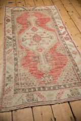 Angled perspective of a vintage Oushak runner with a stepped hexagonal medallion and worn pile.